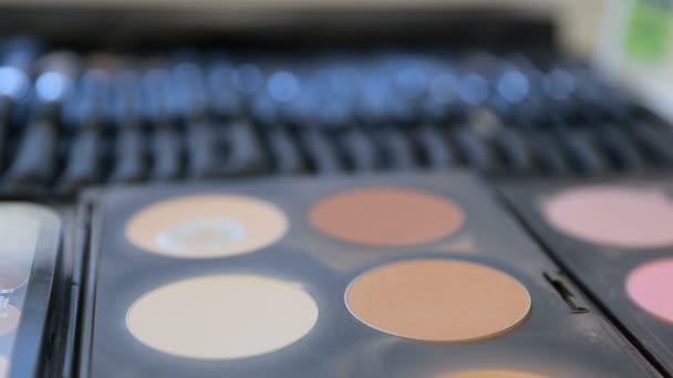 Close up view of makeup brush moving over skin and eyeshadow color palette