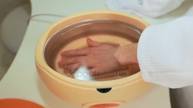 Güzellik salonunda kadın ellerine parafin tedavisi uygula