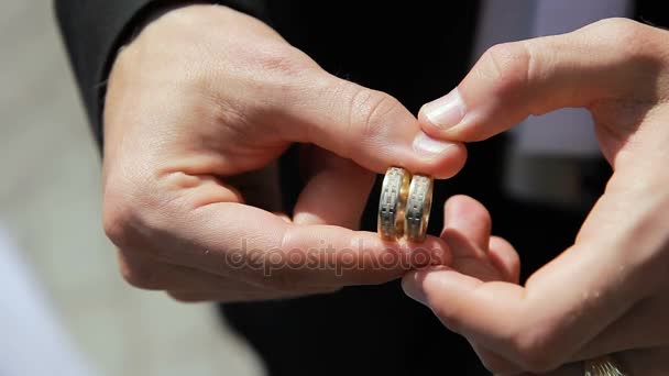 Homem segurando dois anéis de casamento em suas mãos e vira-los — Vídeo de Stock