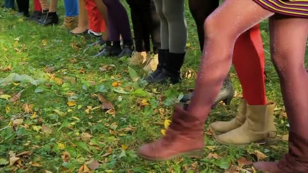 Patas femeninas sobre hierba. Medias de diferentes colores en las piernas de las niñas. Las niñas levantan sus piernas en medias — Vídeos de Stock