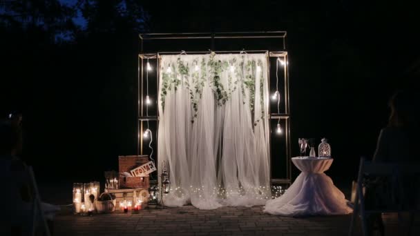 Arco da sposa illuminato prima della cerimonia della prima notte di nozze. Decorazione per una cerimonia di nozze serale, un sacco di candele, atmosfera, torce elettriche — Video Stock