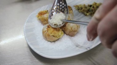 Tuzlu ve garnitürlü bir tabakta servis edilen pişmiş salyangoz. Lüks restoranda nefis pişmiş salyangozlar.