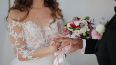 Gelin nikah yüzüğünü damadın parmağına takar. Yüzüklü evlilik elleri.