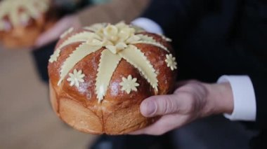Yakın plan düğün geleneği. Bilinmeyen bir adam, yeni evlilerle tanışmak için ziyafet başlamadan bir somun ekmek tutuyor. Düğün ekmeği. Slav düğün gelenekleri. Yeni evlilerle bir somunla tanış..