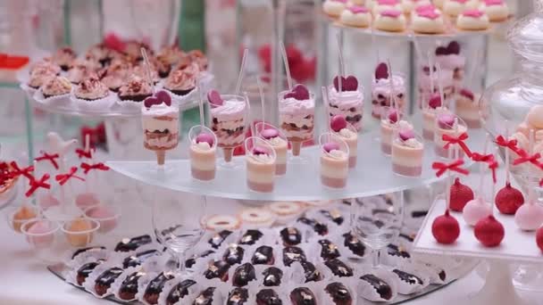 Смачний весільний прийом цукерки бар десертний стіл всередині святкового залу. Весільна випічка на солодкому столі цукерки шведський стіл — стокове відео