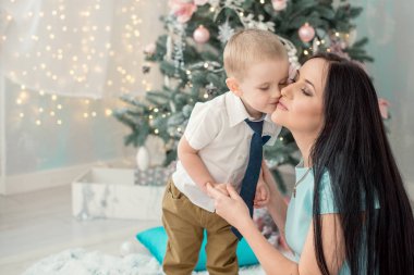 3-4 yıl çocuk annesi içinde belgili tanımlık geçmiş Noel ağacı ve Noel ışıkları öpüşme. Mutlu bir aile kavramı