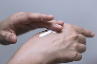 Genç kadın elini güzellik kavramı üzerinde beyaz losyon kullanarak