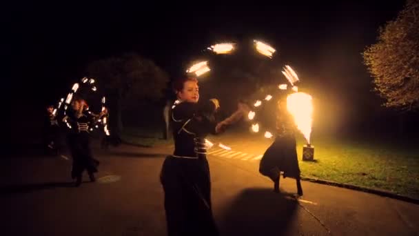 火災ショー。プロのアーティストのグループは、様々 な消防設備を実行します。男の子と女の子が公園の通りに夜の火踊りを実行 — ストック動画