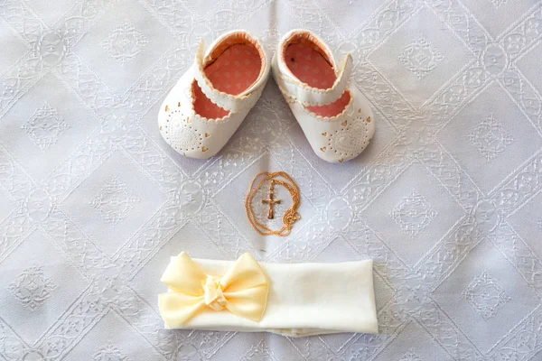 Vaftiz ayrıntılar. Beyaz bebek patik ve bandaj. Beyaz bir tuval üzerine altın haçı