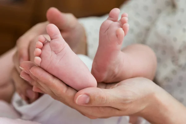 親の手をそっと下から赤ちゃんの足を保持しています。 — ストック写真