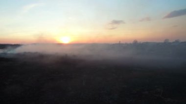 Günbatımında yanan alanlar. Büyük ölçekli yangın, üstten görünüm. Kamera ile kalın duman uçar. Büyük bir alanda smog