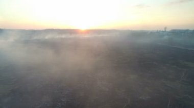Günbatımında yanan alanlar. Büyük ölçekli yangın, üstten görünüm. Kamera ile kalın duman uçar. Büyük bir alanda smog