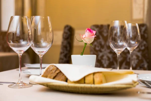 Krásně zdobené stůl v restauraci. Na stole je váza s růžovou růží — Stock fotografie