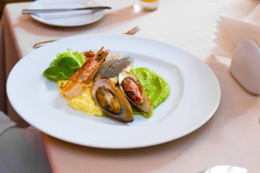 Beyaz bir plaka üzerinde deniz ürünleri. Midye ve karides balık ve yeşil