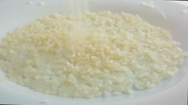 El arroz blanco se vierte seleccionado en un plato que gira. Video alimentos 360 . — Vídeo de stock