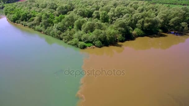 Dois rios de diferentes cores de água se fundem em um grande rio. Vista aérea 4k. Voando sobre o belo rio. Câmara aérea disparada. Panorama da paisagem . — Vídeo de Stock