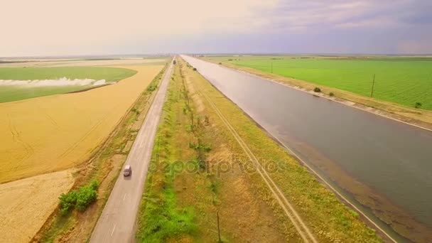 Wasserkanal zwischen den grünen und gelben Weizenfeldern zur Eingemeindung — Stockvideo