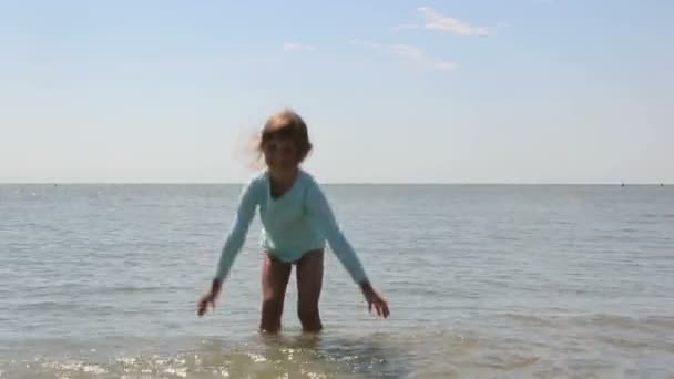 En liten flicka njuter av havet bevattnar — Stockvideo