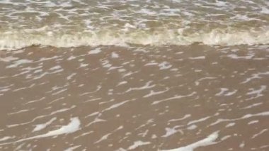 Deniz suyu kum plaj güneşli bir günde yıkar.