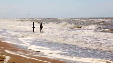 İki genç çocuklar denizde fırtına sırasında dalgalar zevk