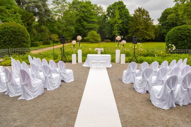 Düğün töreni parkta toplayan. Beyaz bir çerçeve çiçeklerle süslenmiş. Beyaz stil törenle