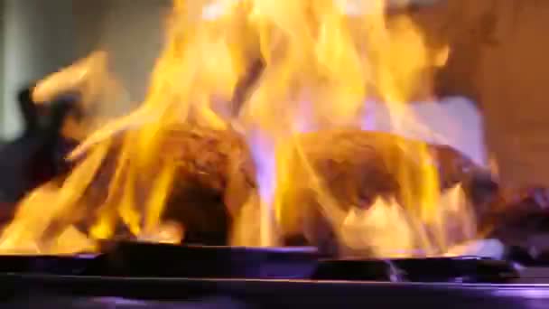 El chef profesional prepara una comida en el restaurante. Un pedazo de carne arde en el fuego con una bebida de alcohol . — Vídeo de stock