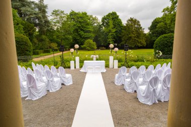 Düğün töreni parkta toplayan. Beyaz bir çerçeve çiçeklerle süslenmiş. Beyaz stil törenle