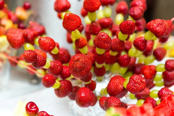 Uvas de fresa en un palo. Fruta en un palo en una mesa de banquete — Foto de Stock