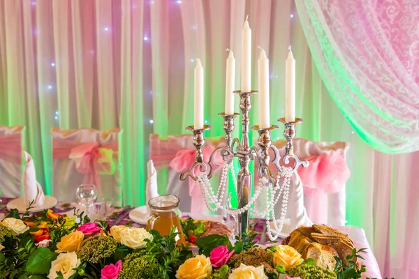 Kerzenständer auf einem Banketttisch auf rosa-grünem Hintergrund — Stockfoto