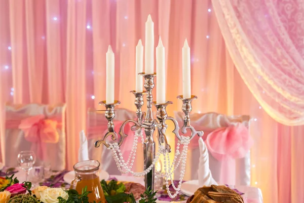 Candelero sobre una mesa de banquete en cálidos fondos naranjas —  Fotos de Stock