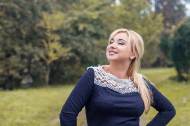 Bir parkta güzel kız model fotoğraf makinesi için poz.