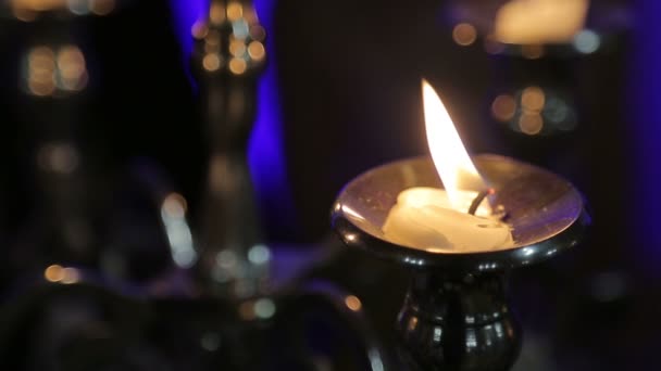 One candle on a table on a black background blazes — Stock Video