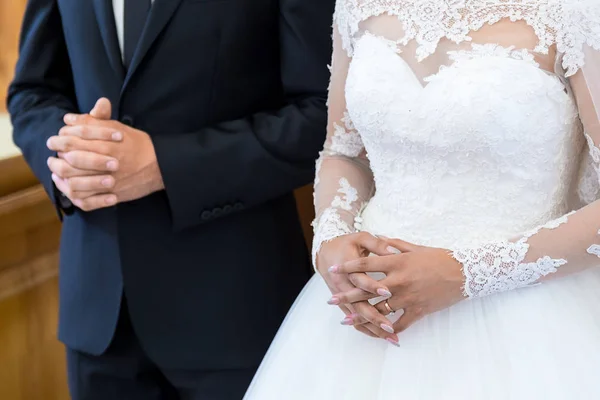 Oigenkännlig bruden och brudgummen i kyrkan under kristna bröllopsceremonin. Händerna på brudar som närbild i kyrkan — Stockfoto