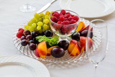 İki kişilik bir masa ile ahududu, üzüm ve Erik meyve tabak açıktır