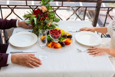Gelin ve damat var olduğu bir tabak meyve bir masada oturuyor.