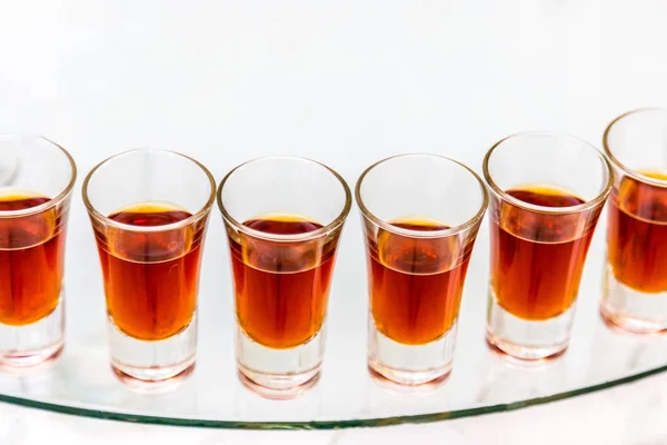 Servicios de catering. Celebración. vasos de alcohol rojo colocados en el vidrio —  Fotos de Stock