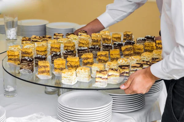 Os garçons põem em uma mesa de bufete uma massa doce — Fotografia de Stock