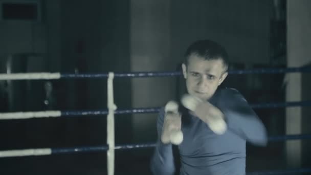 Boxeador en el ring entrena golpes rápidos. preparándose para la batalla. Fondo oscuro — Vídeos de Stock