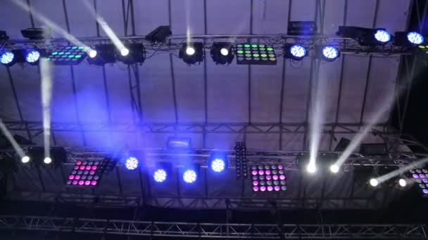 Iluminando la gran escena. Las luces intermitentes en diferentes colores se mueven en diferentes direcciones. Luz en conciertos, discotecas, clubes nocturnos . — Vídeos de Stock