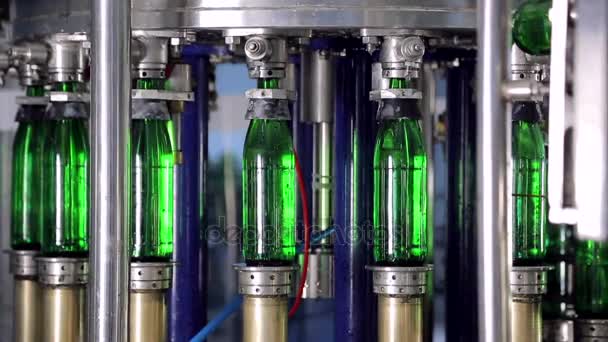 Line of water production. Green glass bottles move automatically along the lines of production, and fill with water — Stock Video