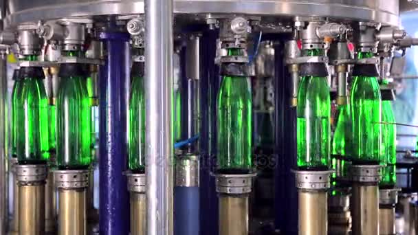 Линия производства воды. Зеленые стеклянные бутылки автоматически перемещаются по линиям производства и заполняются водой — стоковое видео