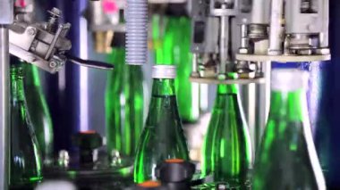 Şişe kapakları su tesisi ile otomatik olarak kapsayan. Yeşil cam şişeler otomatik konveyör hattı üzerinde.