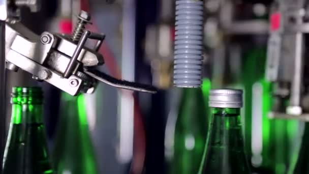 Автоматическое накрытие бутылок крышками в водяной установке. Зеленые стеклянные бутылки на автотранспортерной линии. Закрыть — стоковое видео
