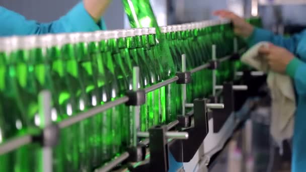 Сотрудник производственной линии вытирает стеклянные бутылки для минеральной воды — стоковое видео