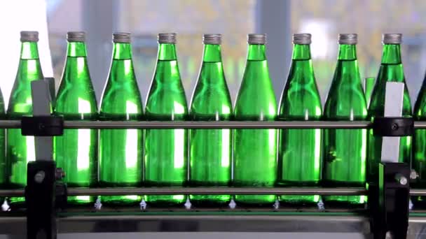 Зелені пляшки для мінеральної води рухаються вздовж автоматичної виробничої лінії . — стокове відео