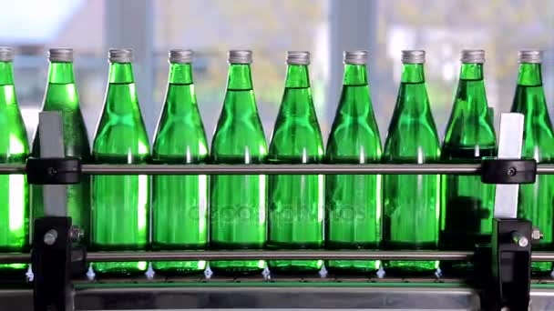 Botellas verdes para agua mineral se mueven a lo largo de la línea de producción automática . — Vídeos de Stock