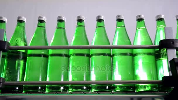 Botellas verdes para agua mineral se mueven a lo largo de la línea de producción automática . — Vídeo de stock