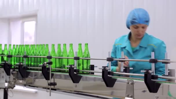 Lijn van waterproductie. De werknemer legt de glazen flessen op de lijn van automatische reiniging en het vullen van flessen met water. — Stockvideo