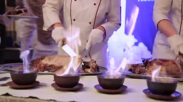 Der Kellner schneidet Fleisch. Einfangen einer Kamera durch ein Feuer — Stockvideo