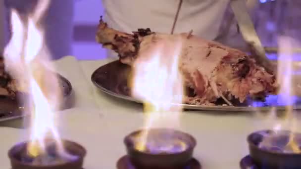 Der Kellner schneidet Fleisch. Einfangen einer Kamera durch ein Feuer — Stockvideo